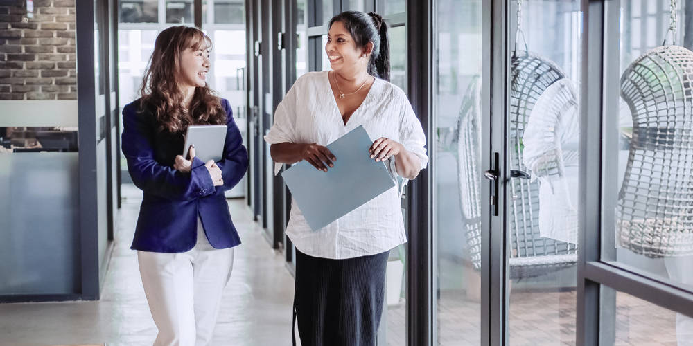 Two women walking and talking in an office building