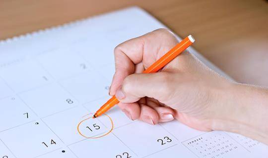 person circling date on calendar