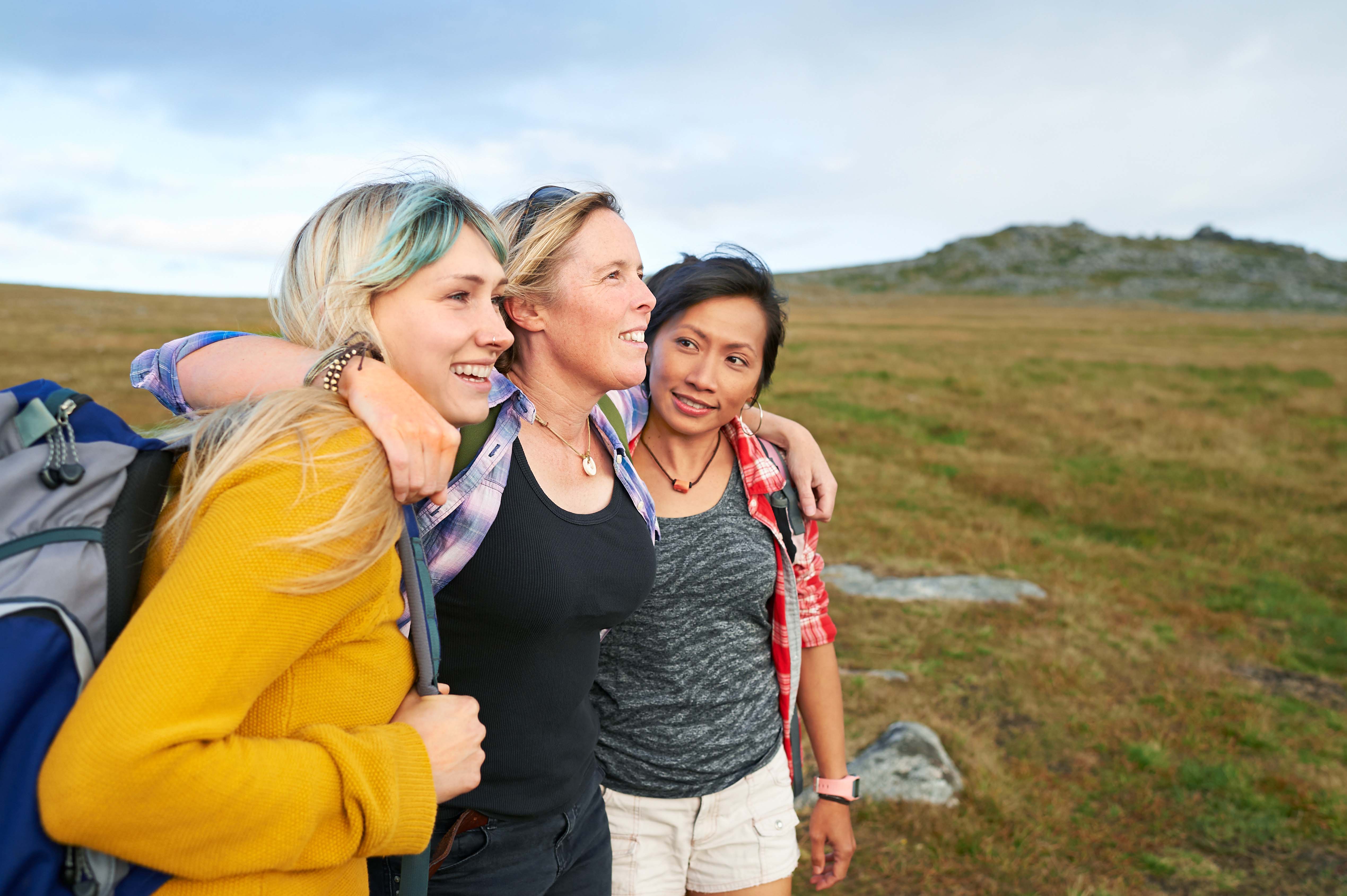 A group of hiking friends huddle together on a rocky moorland in an idyllic rural countryside.