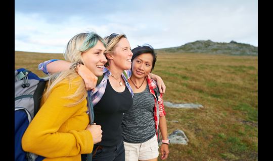 A group of hiking friends huddle together on a rocky moorland in an idyllic rural countryside.