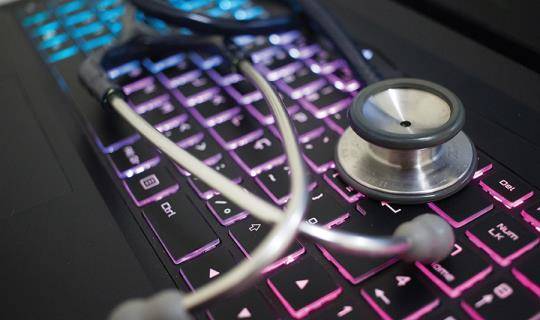 Stethoscope laying on top of a glowing keyboard