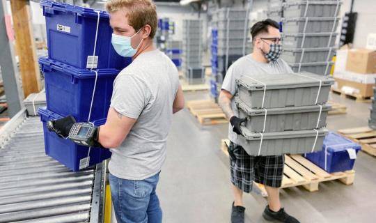 Workers carry totes at a DC
