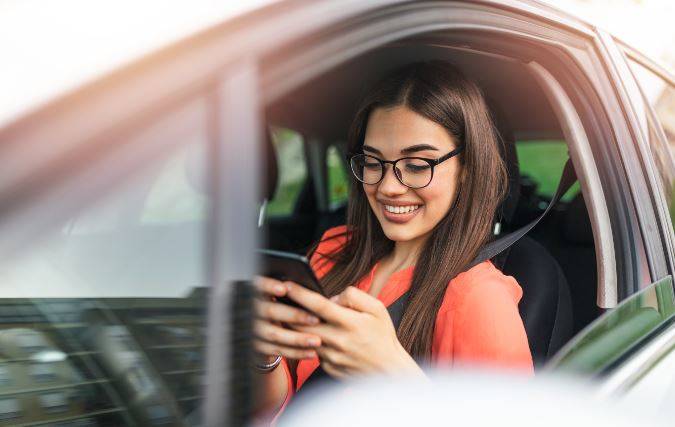 Woman sitting in car using phone