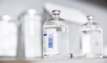 Pharmaceutical bottles on counter next to syringe