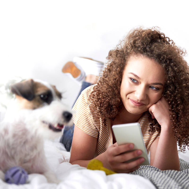 women with her phone in her hand and she is looking at her small dog