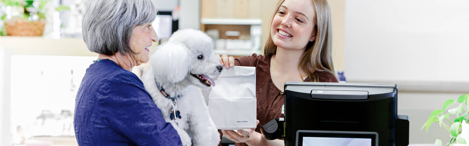 woman holding dog at pharmacy counter