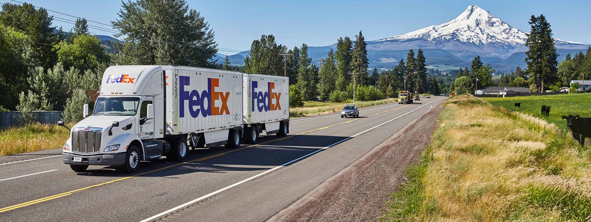 FedEx truck driving on road with mountain in the background
