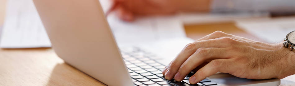 person's hands working on laptop and taking notes