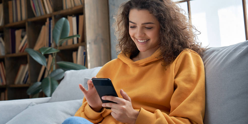 Girl on couch using MWI Mobile App to shop for products
