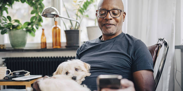 man scrolling through phone with dog on his lap
