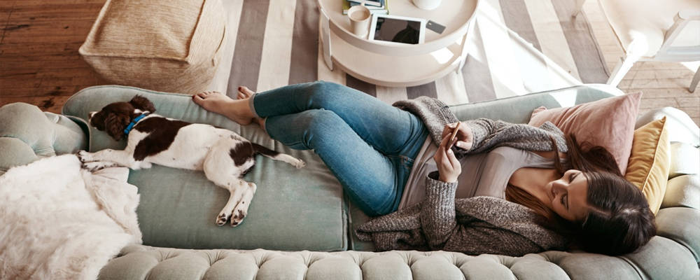 Woman lying on the couch with her dog