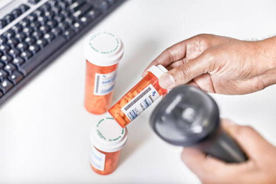 Hands using a scanner to scan the barcode on a bottle of medication